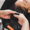 Hairdresser putting mask and coloring on woman's hair in beauty salon, Professional hairdresser dyeing hair of her client, Process of dyeing hair at beauty salon