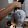 Beautician drying senior woman hair reflecting on mirror in salon