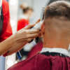 European man is cut by a barber. Men's hairstyling and haircutting with hair clipper in a barber shop or hair salon