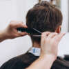 Master cuts hair and beard of men in the barbershop, hairdresser makes hairstyle for a young man