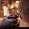 Male haircut trimming in barbershop, client getting haircut by hairdresser with clipper and hairbrush. Hairdresser makes hairdo in hairdresser salon, new stylish modern haircut for man
