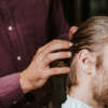 cropped view of barber touching hair of man