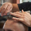 Selective focus on the hands of a professional barber giving his client a haircut.